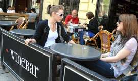 Zwei junge Frauen sitzen in einer Weinbar bei Rot- und Weisswein