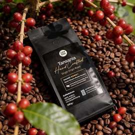Eine Packung Tansania Single Origin Roast auf einem Korb ger�steter Kaffeebohnen, daneben ein paar frische, rote Kaffeebohnen am Zweig