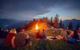 Zahlreiche G�ste geniessen ein Sonnwendfeuer in den Bergen bei Saalbach