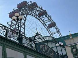 Das Riesenrad im Wiener Prater vor blitzblauem Himmel, im Vordergrund das Schild 'Prater - hereinspaziert!'
