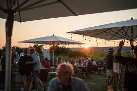 Sonnenuntergang, davor relaxte Leute unter Sonnenschirmen bei Wien O'Clock