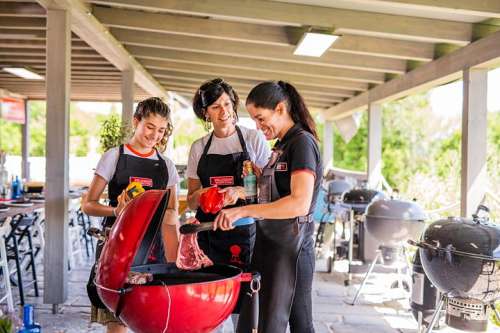Grillmeisterin Yulia Haybck in der Weber Grillakademie Velden mit zwei aufmerksamen Lernenden