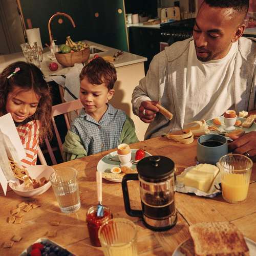 Ein Mann sitzt mit zwei Kindern am Fr�hst�ckstisch