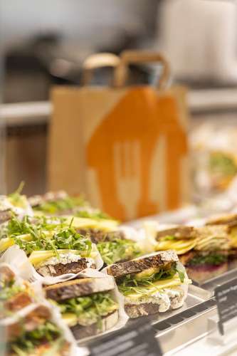 Ein Tablett mit Ruccula-K�se-Sandwiches vor einem Papiersackerl mit Lieferando-Logo