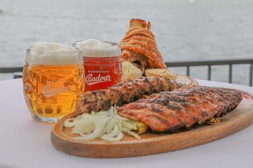 Ein Teller Grillripperl, dahinter zwei Gl�ser Budweiser, im Hintergrund eine knusprige Stelze