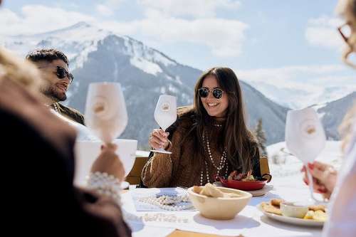 Kulinarik bei den White Pearl Mountain Days 2026: junge Menschen stossen an einem Tisch vor der herrlichen Bergkulisse an